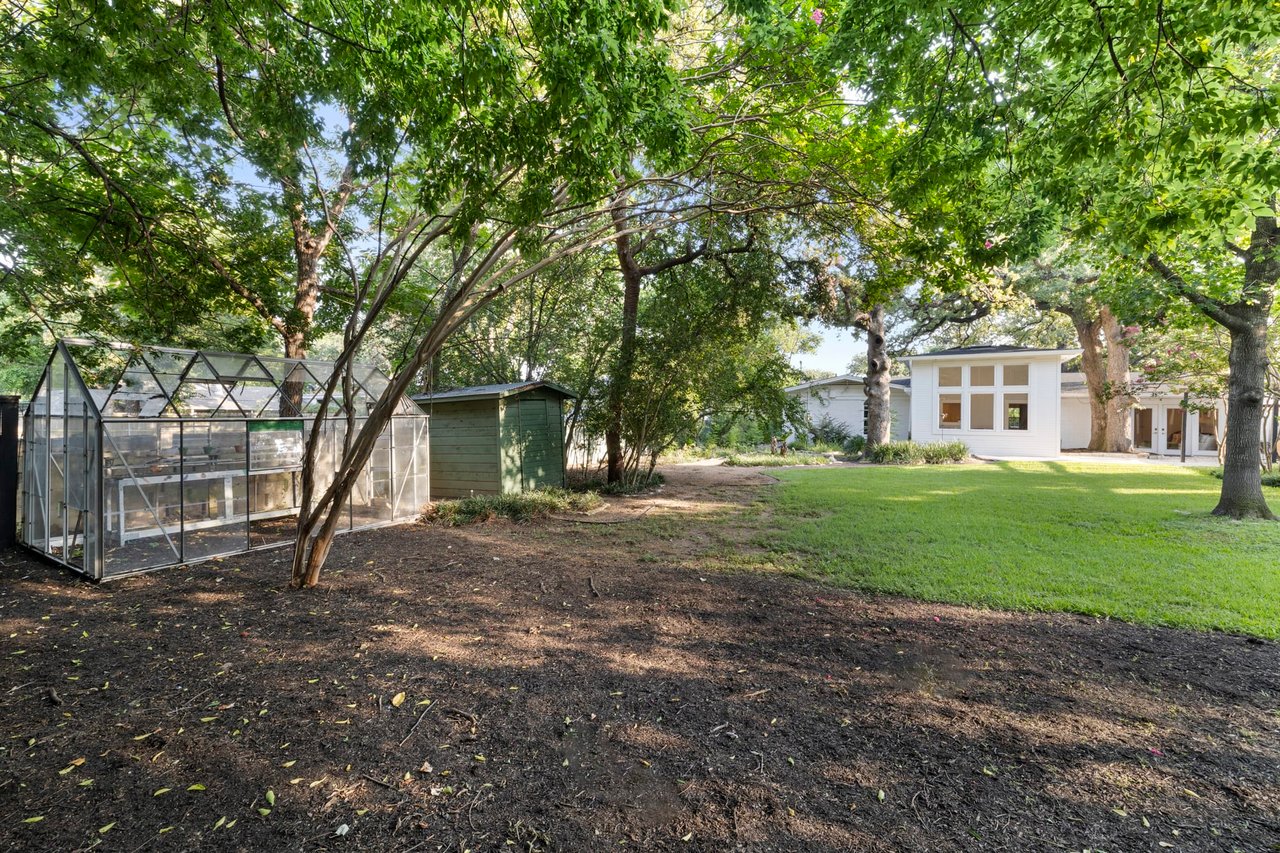 Side yard with a greenhouse structure on the wooded lot, Tarrytown, Austin.