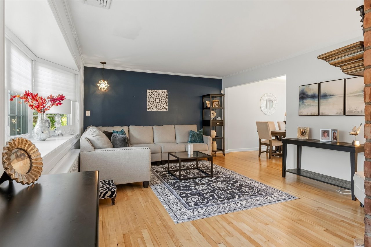Living room with a light sectional, dark blue accent wall, patterned rug, and hardwood floors.