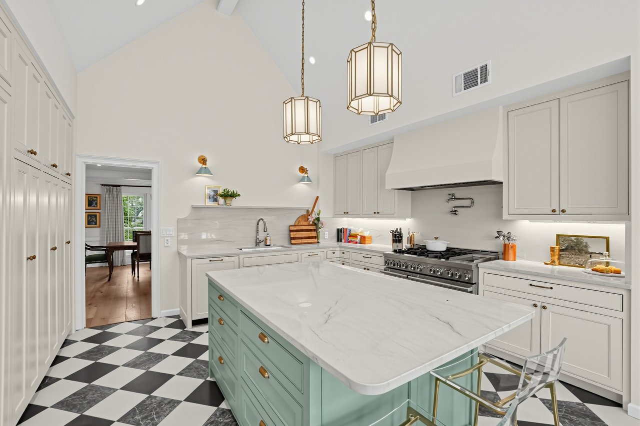 Kitchen with a pale green island, checkerboard floor, and white cabinetry.
