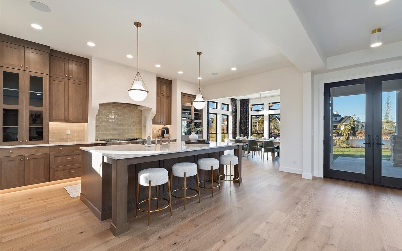 Wide view of the kitchen, dining room and the see-through double doors leading out to the backyard