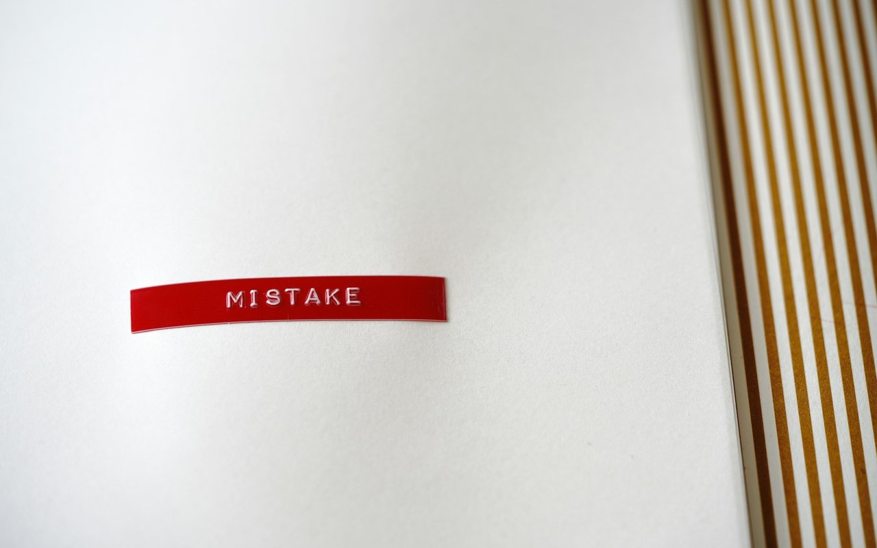 Red strip labeled “MISTAKE” on a white surface beside vertical wooden slats.