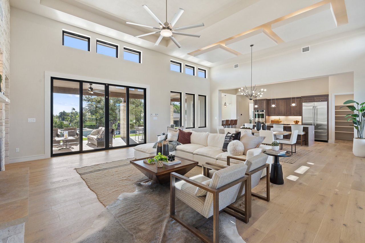 Great room with vaulted ceilings and a wall of windows opening to the kitchen, in this Caudill Lane home in the Bee Caves area of Austin, Texas.