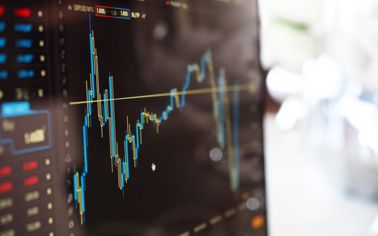 Financial market chart with fluctuating blue and yellow price lines on a trading screen.