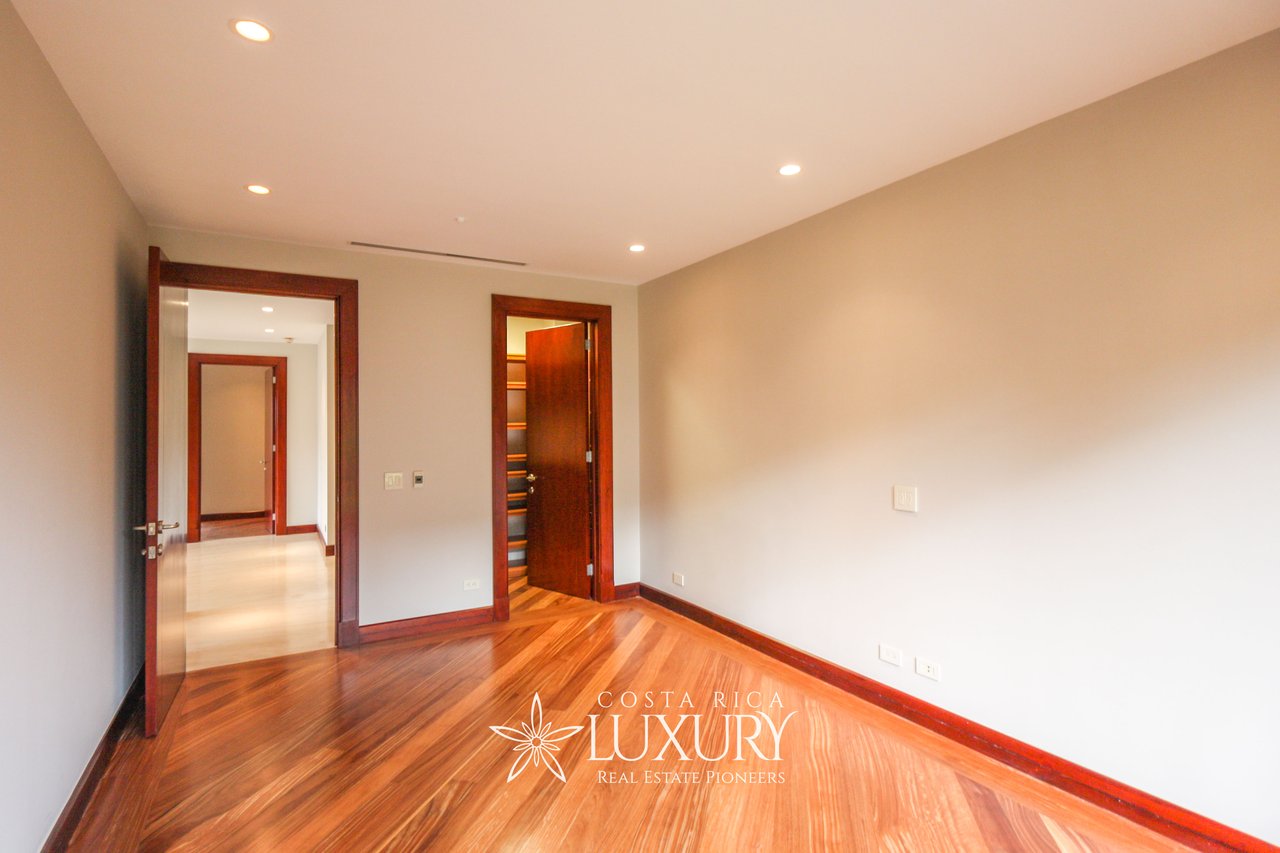 Empty apartment room with polished hardwood floors and an open doorway to built-in shelving.