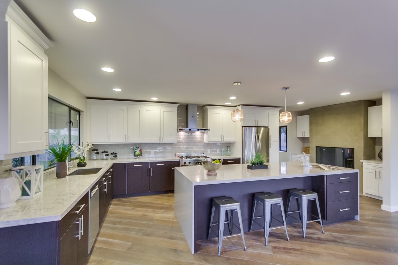 Modern kitchen with a large island, dark cabinets, stainless appliances, and a fireplace.