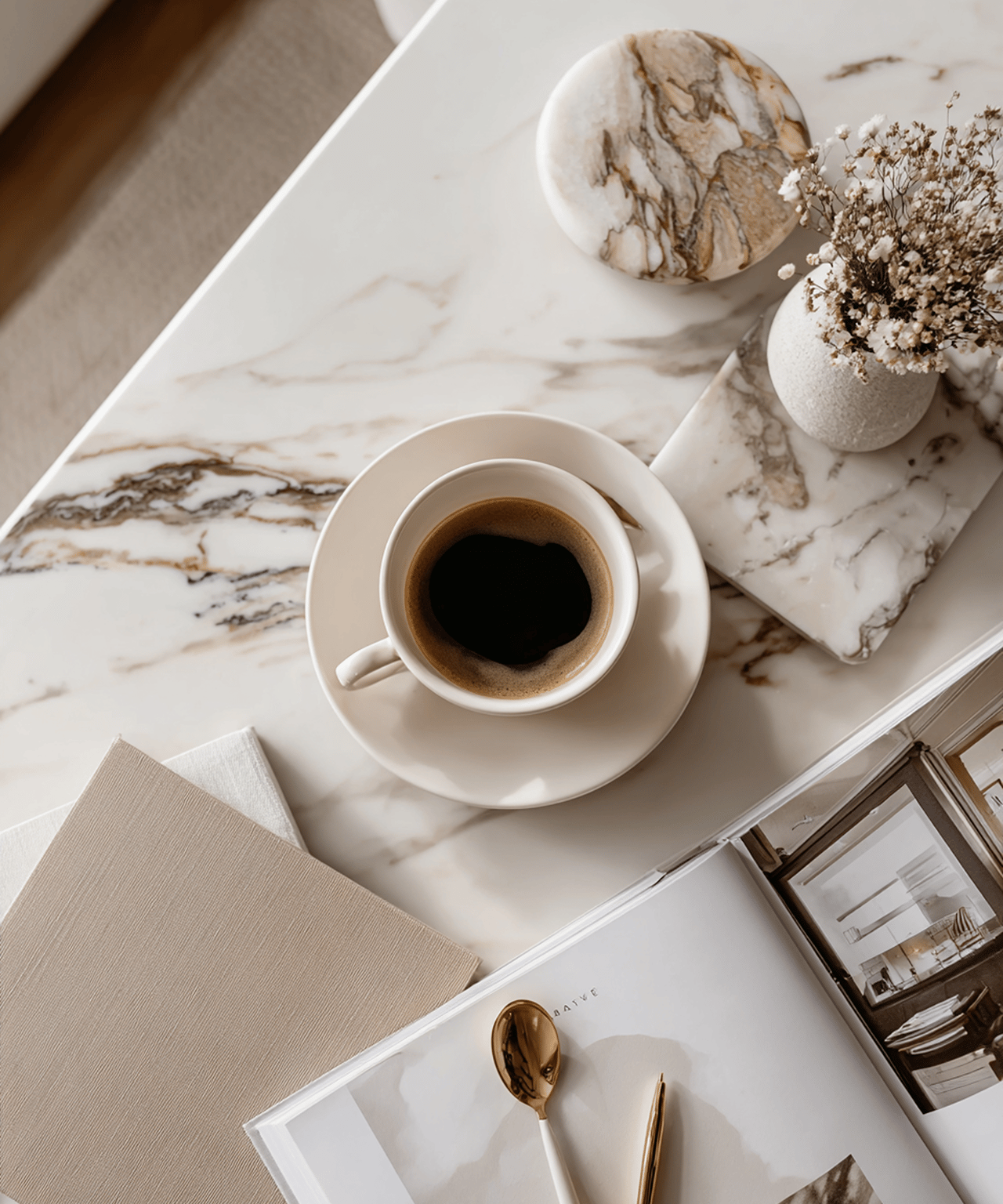Black coffee on a marble surface beside dried flowers and neutral interior design materials.