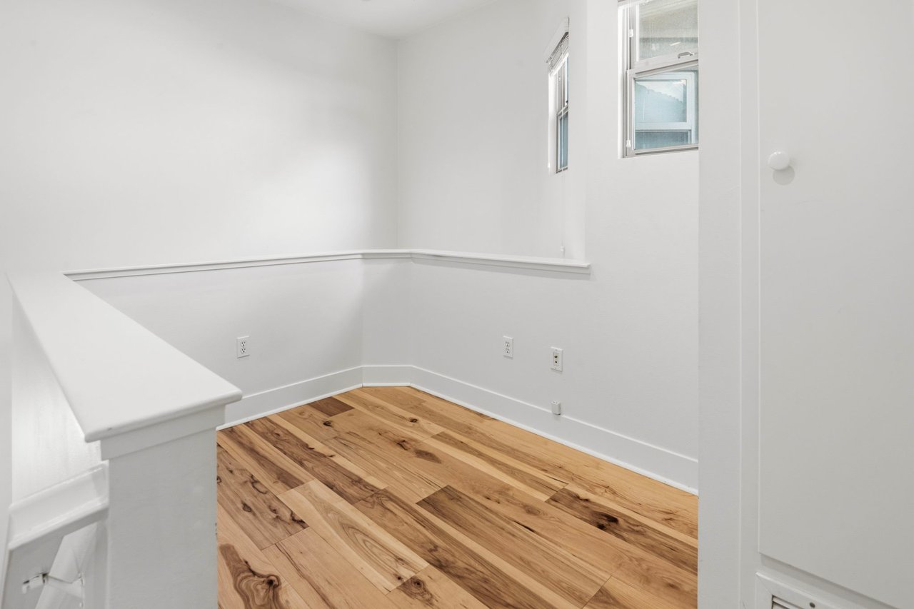 Kitchen pantry nook with built-in shelving, hardwood floors, and natural light from upper window
