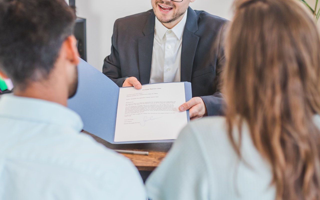 Mortgage adviser presents a document to a couple during a consultation.