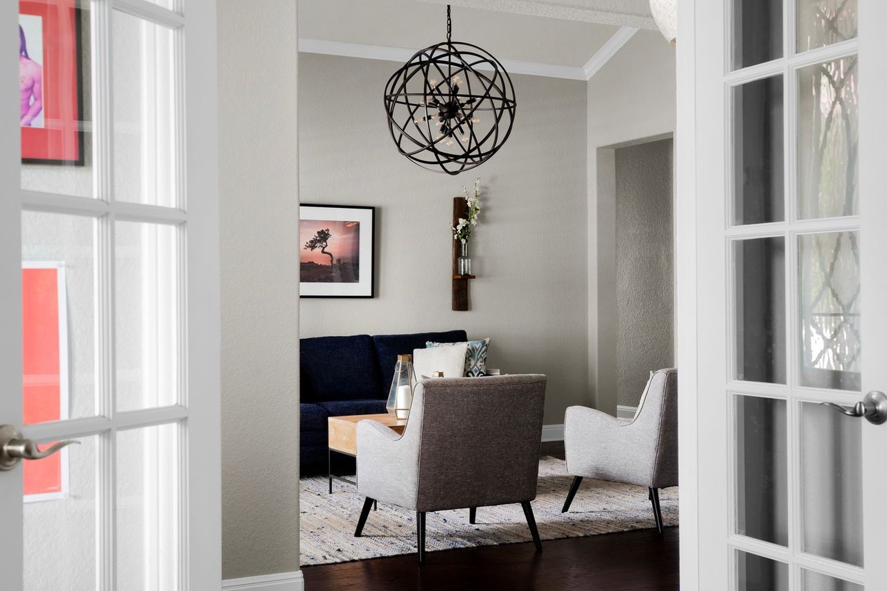 Furnished living room with a dark blue sofa, two armchairs, and a spherical black chandelier.