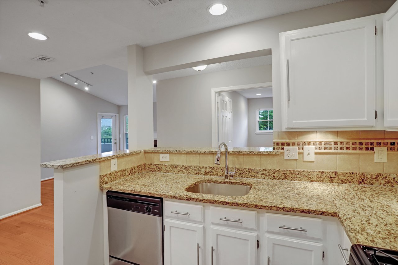 Kitchen with granite counters, white cabinetry, and a pass-through to the adjoining living area.