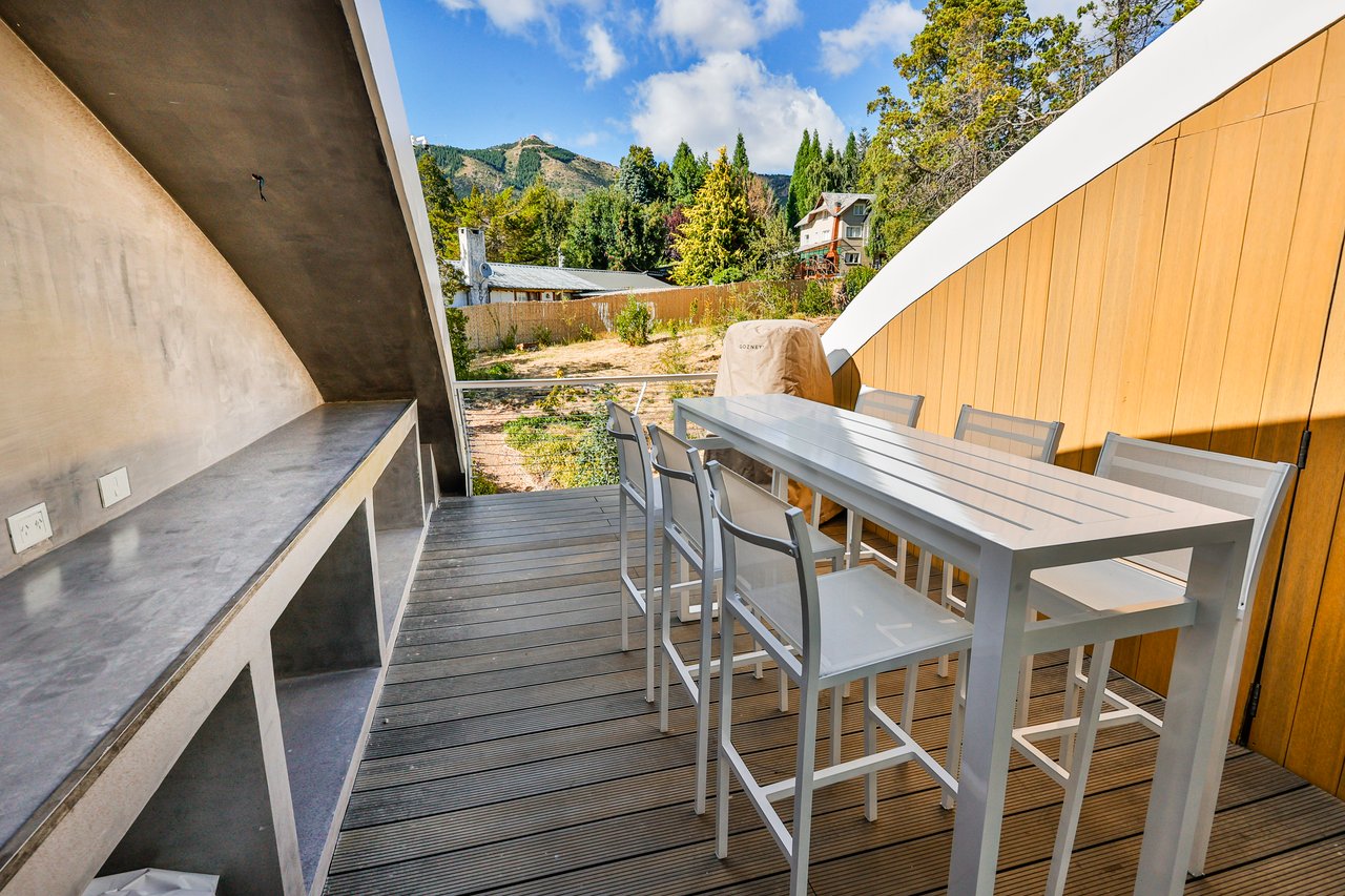 Outdoor dining deck with a long table, built-in counter, and mountain views.