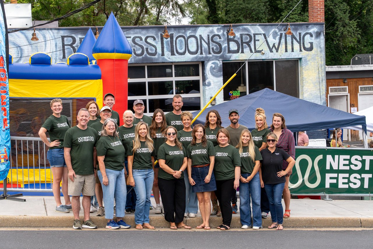 Nest Realty team members pose outside a brewery beside a colorful inflatable castle.