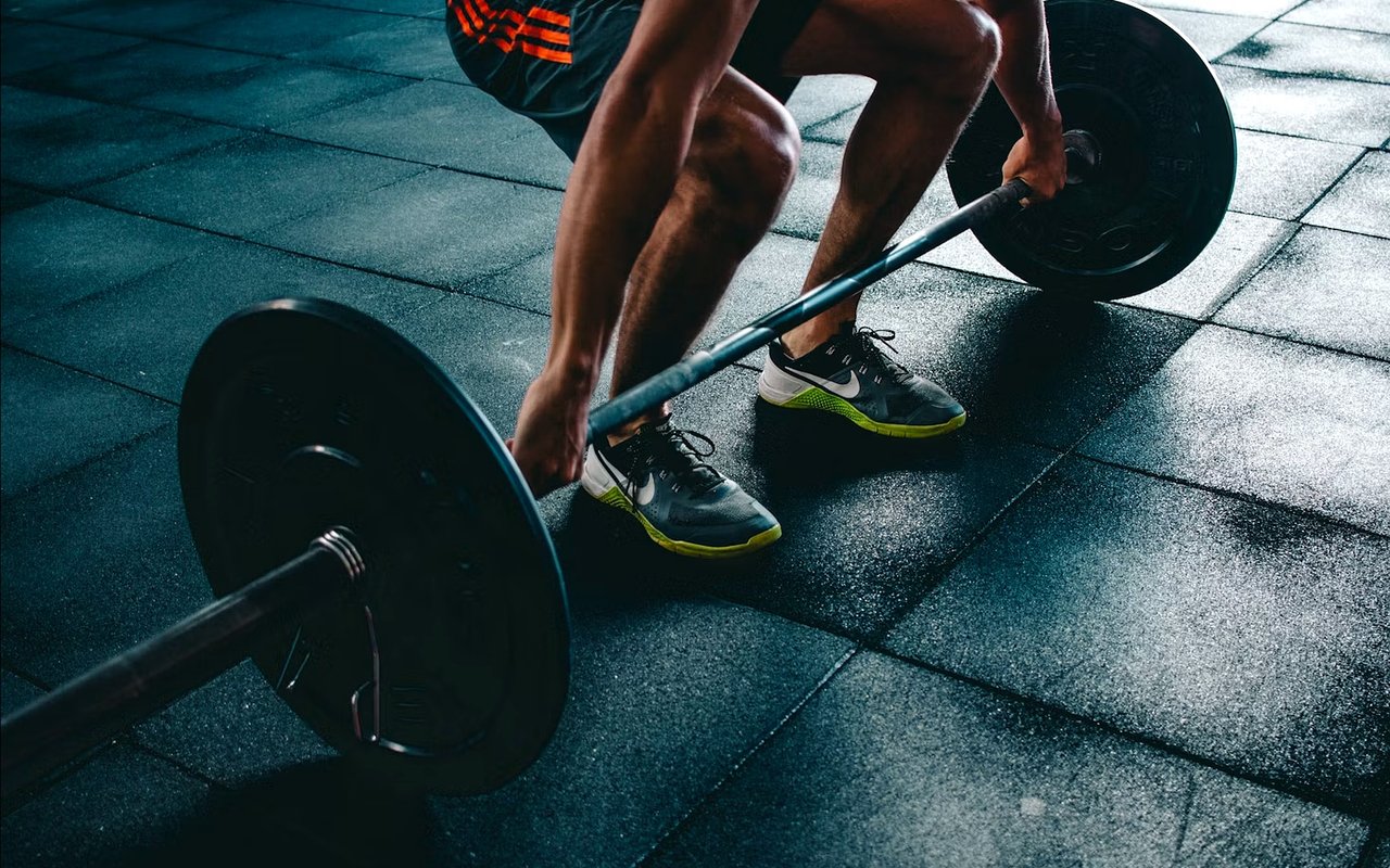 A gym-goer grips a loaded barbell while preparing to lift.