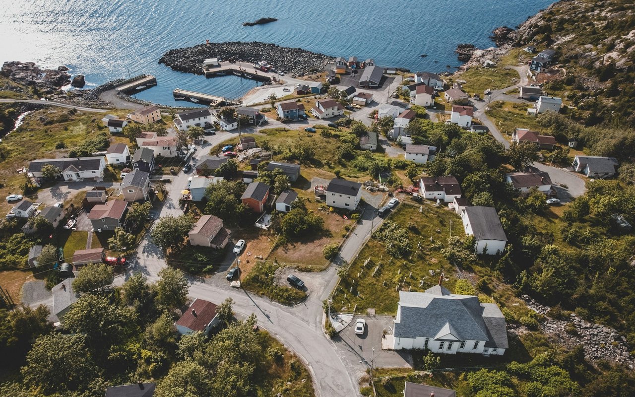 Coastal neighborhood surrounding a small harbor, with houses and rocky shoreline.