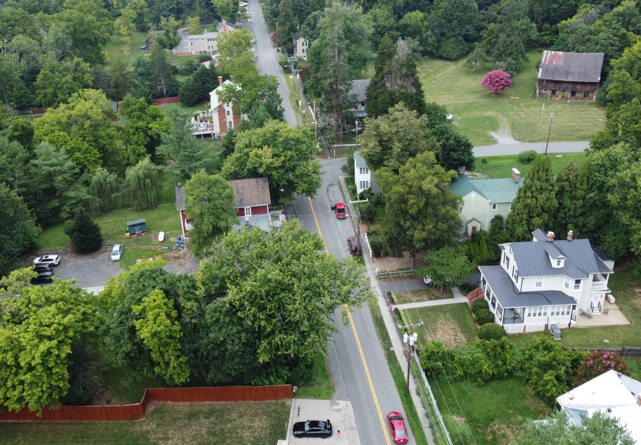 An elevated aerial drone shot capturing the historic village, rolling countryside, and Blue Ridge Mountain backdrop of Bluemont, VA in Western Loudoun County, photographed by local real estate expert Diana Geremia.