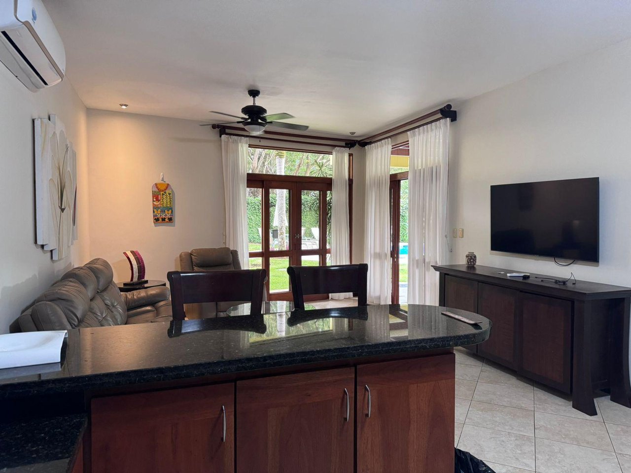Condo living room with a stone breakfast bar, leather seating, and glass doors to a garden.