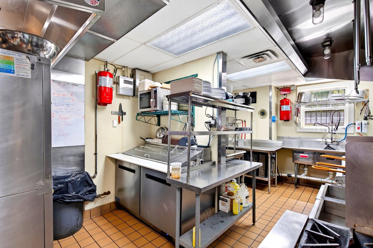 Commercial restaurant kitchen with stainless-steel prep counters, dish shelving, and a large sink.