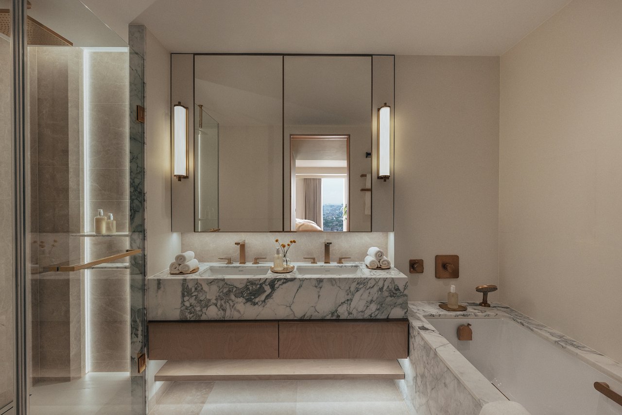 Luxury bathroom with a marble double vanity, glass shower, and marble-surrounded bathtub.