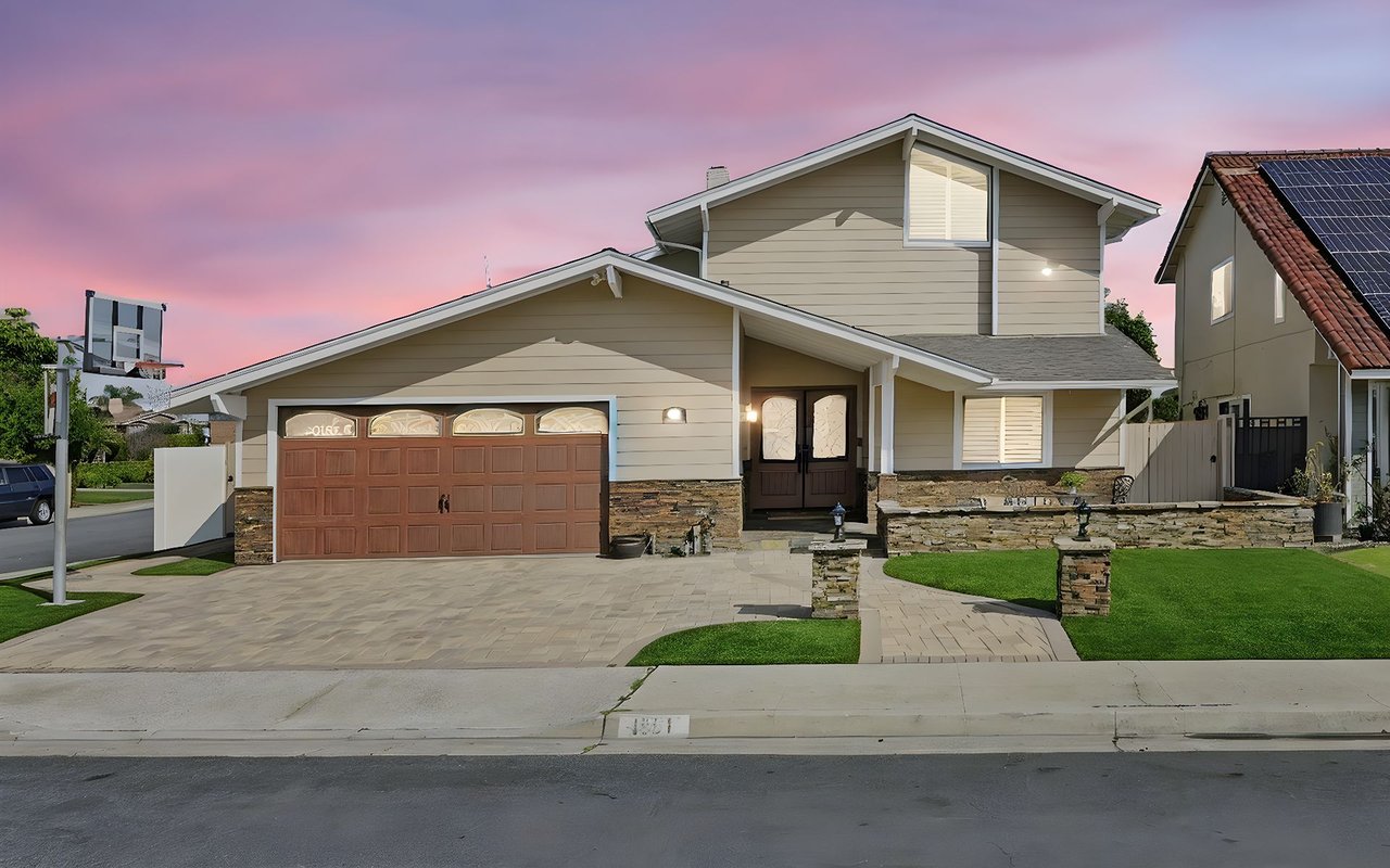 La Palma home with beige siding, stone accents, and a basketball hoop at dusk.