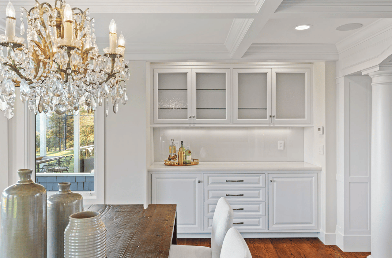 Dining room with a crystal chandelier, dark wood table, and white built-in cabinetry.