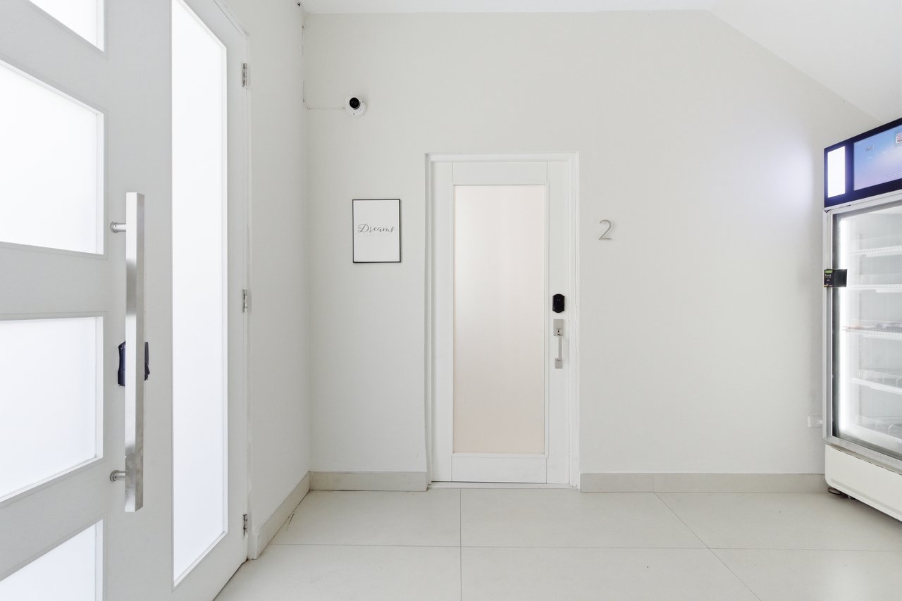 Bright entry area with frosted-glass entrance door, numbered door 2, and glass-front refrigerator.