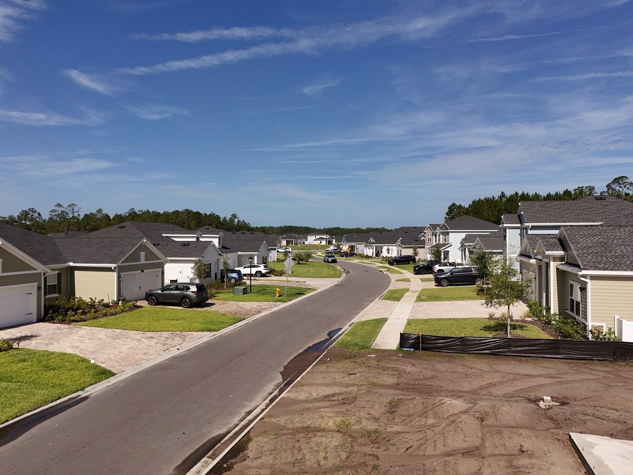 Residential street in Silver Meadows with detached homes, parked cars, and a curving road.