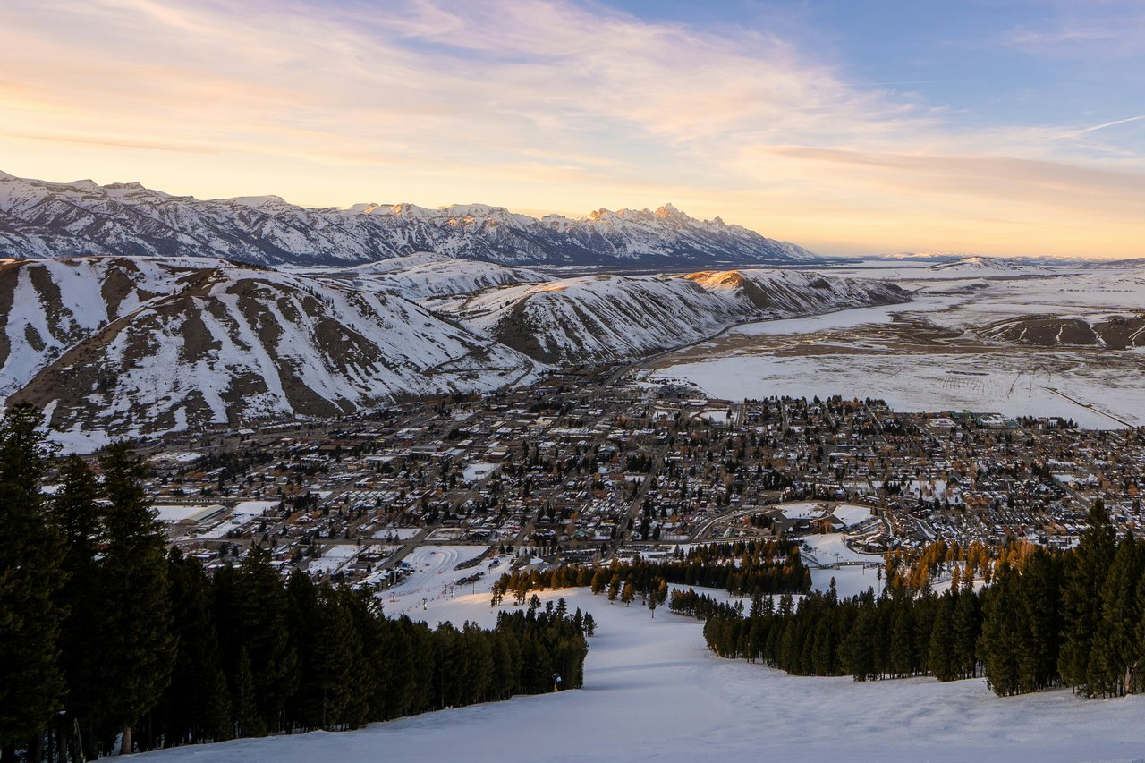 Snow-covered Jackson Hole town and valley beneath the Teton Range at sunset.