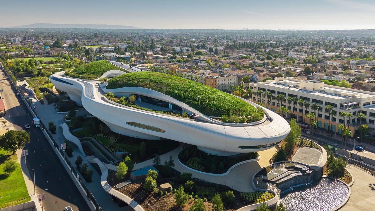 Modern building with sweeping white curves and a planted green roof, seen above Palm Springs.