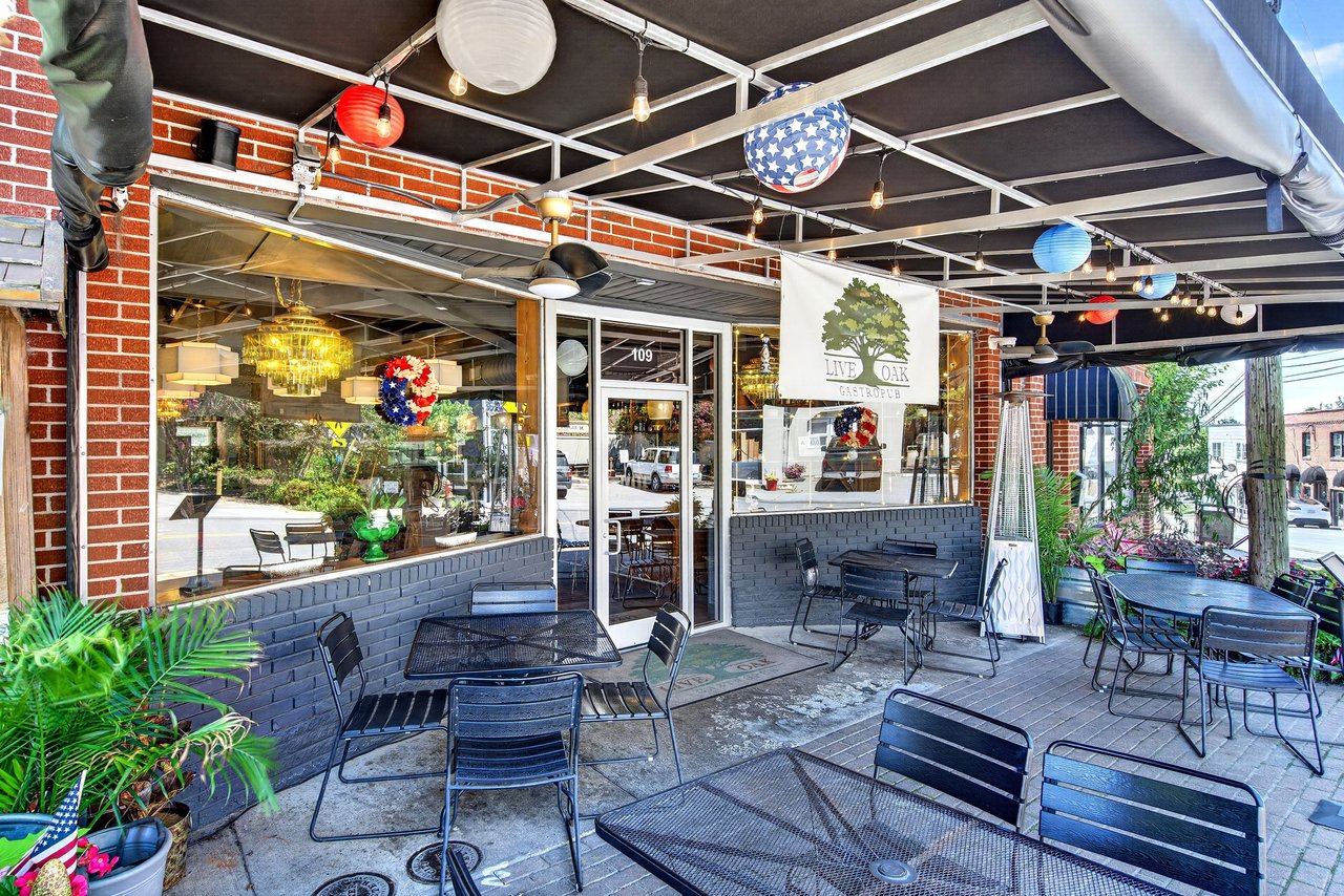 Restaurant storefront with covered patio dining, brick walls, string lights, and Live Oak Gastropub banner.
