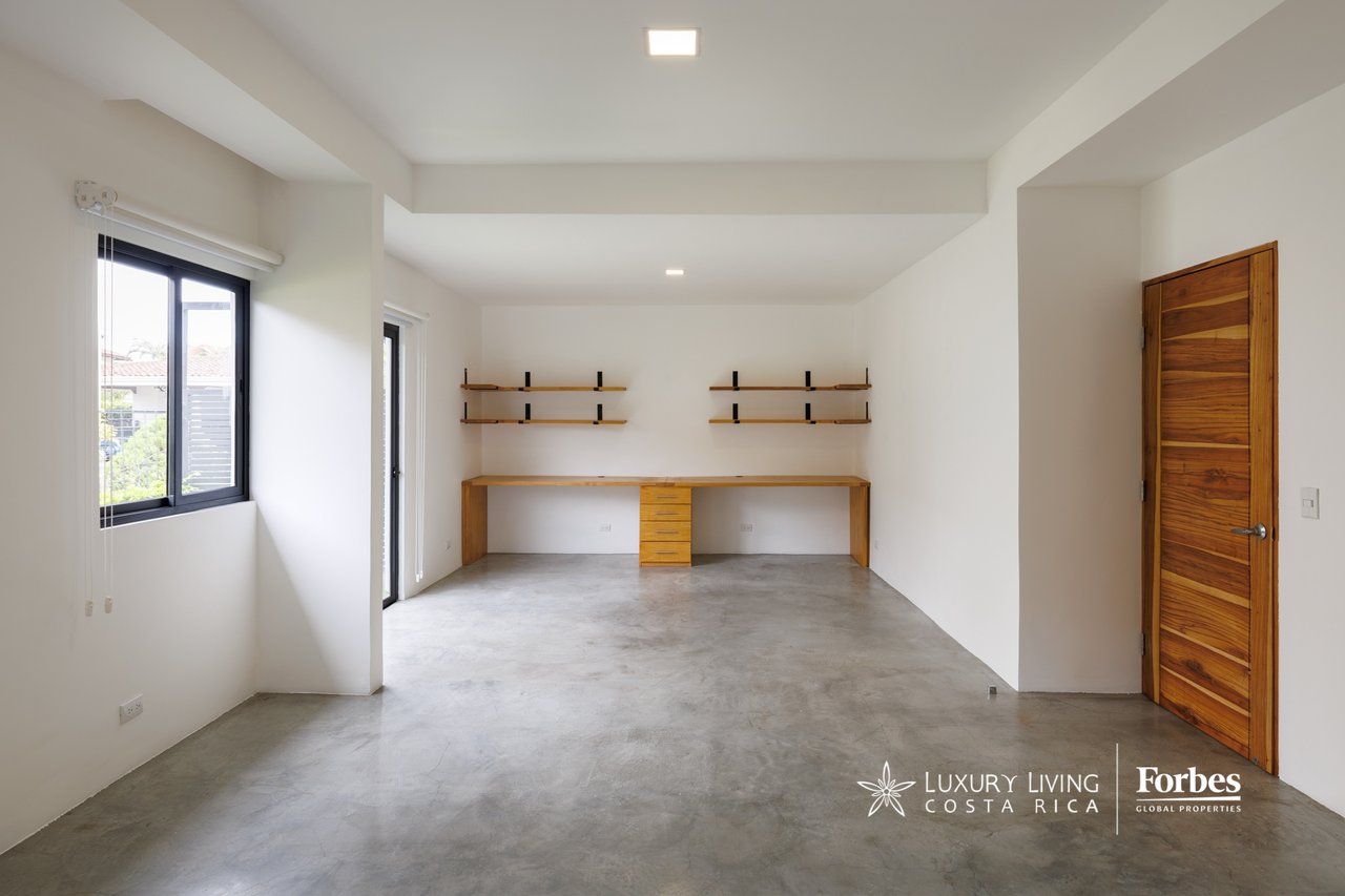Unfurnished room with a built-in wooden desk, floating shelves, concrete floor, and large window.