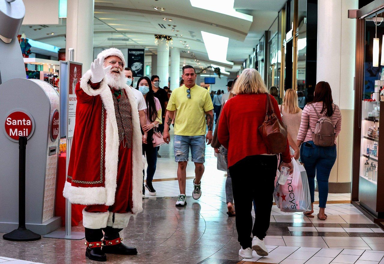 Shoppers walking through a Miami outdoor mall on Black Friday with holiday lights and decorations.