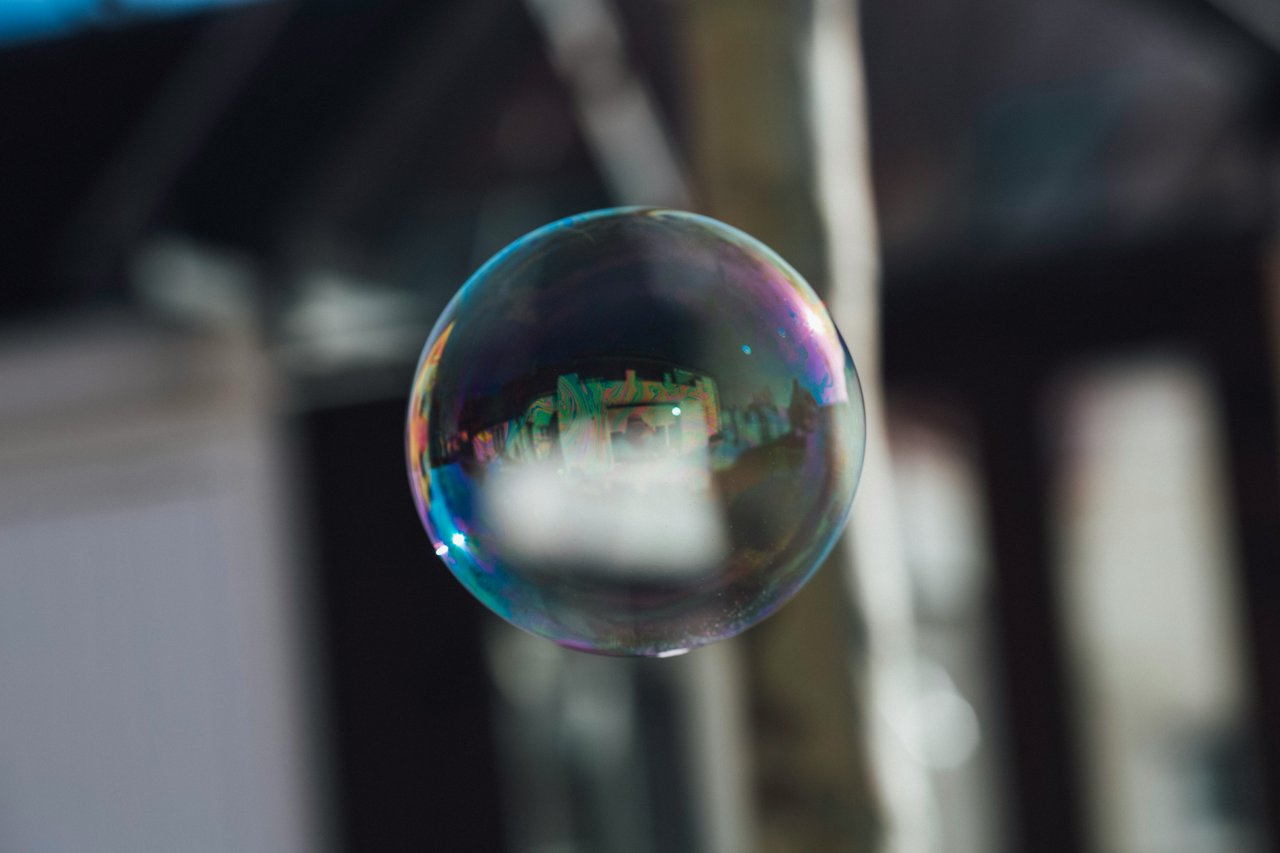 Iridescent soap bubble floating against a blurred indoor background.