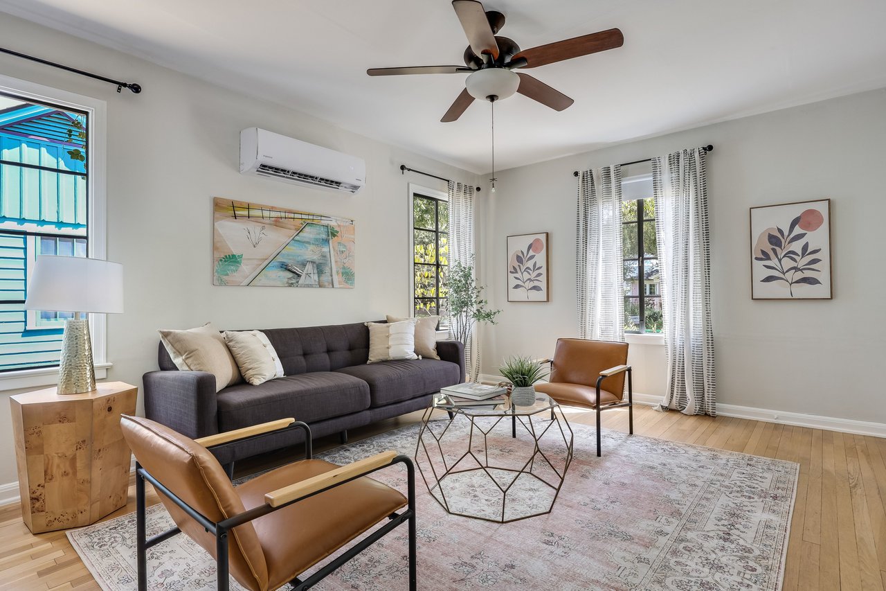 Living room with a charcoal sofa, brown leather chairs, and tall curtained windows.