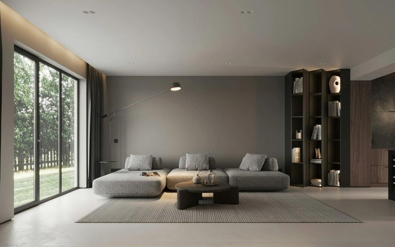 Modern living room with a low gray sofa, dark built-in shelves, and glass doors overlooking a yard.