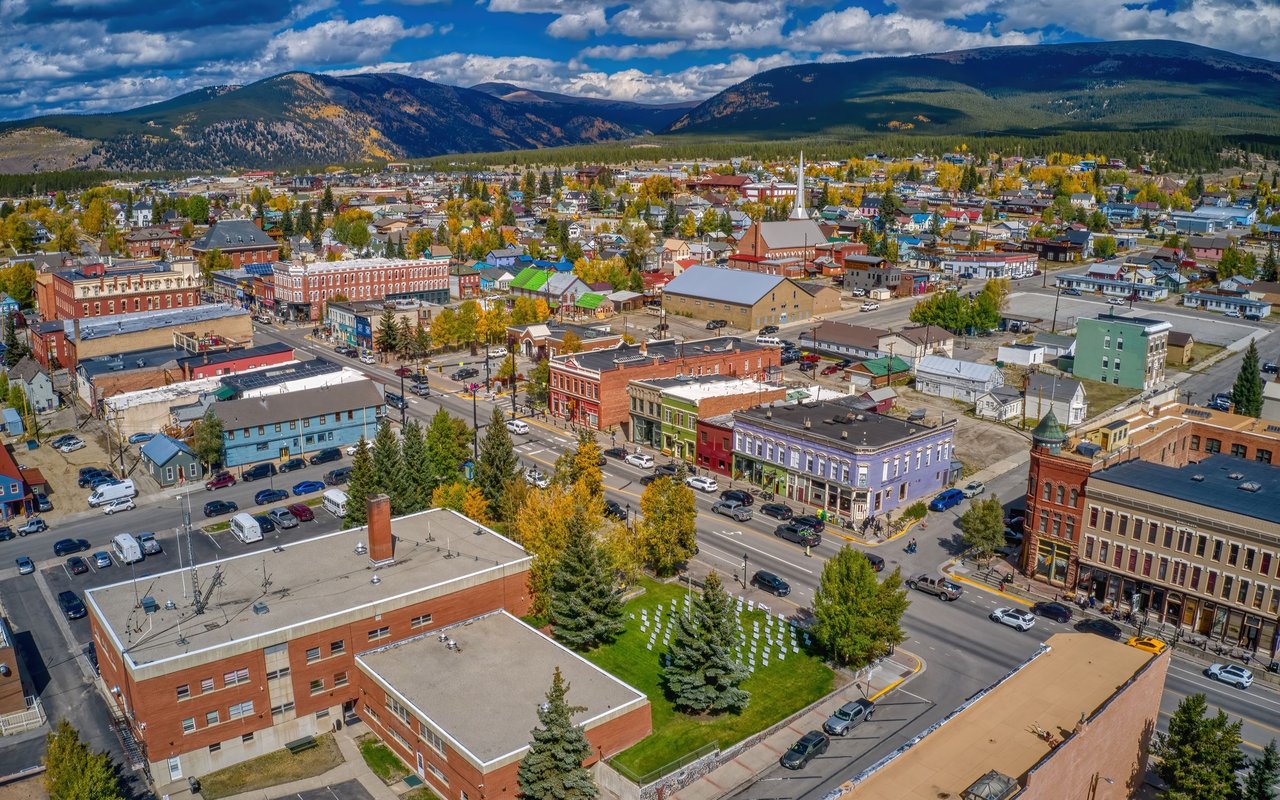 Aerial view of Leadville’s colorful downtown and autumn foliage beneath surrounding mountains.