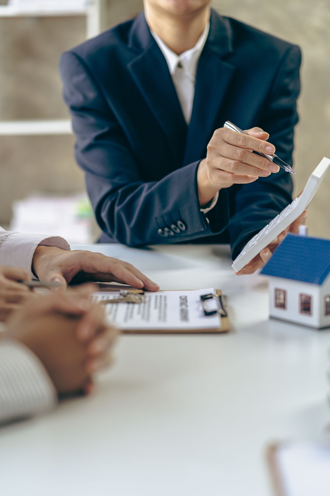 People reviewing real estate documents beside a small model house.