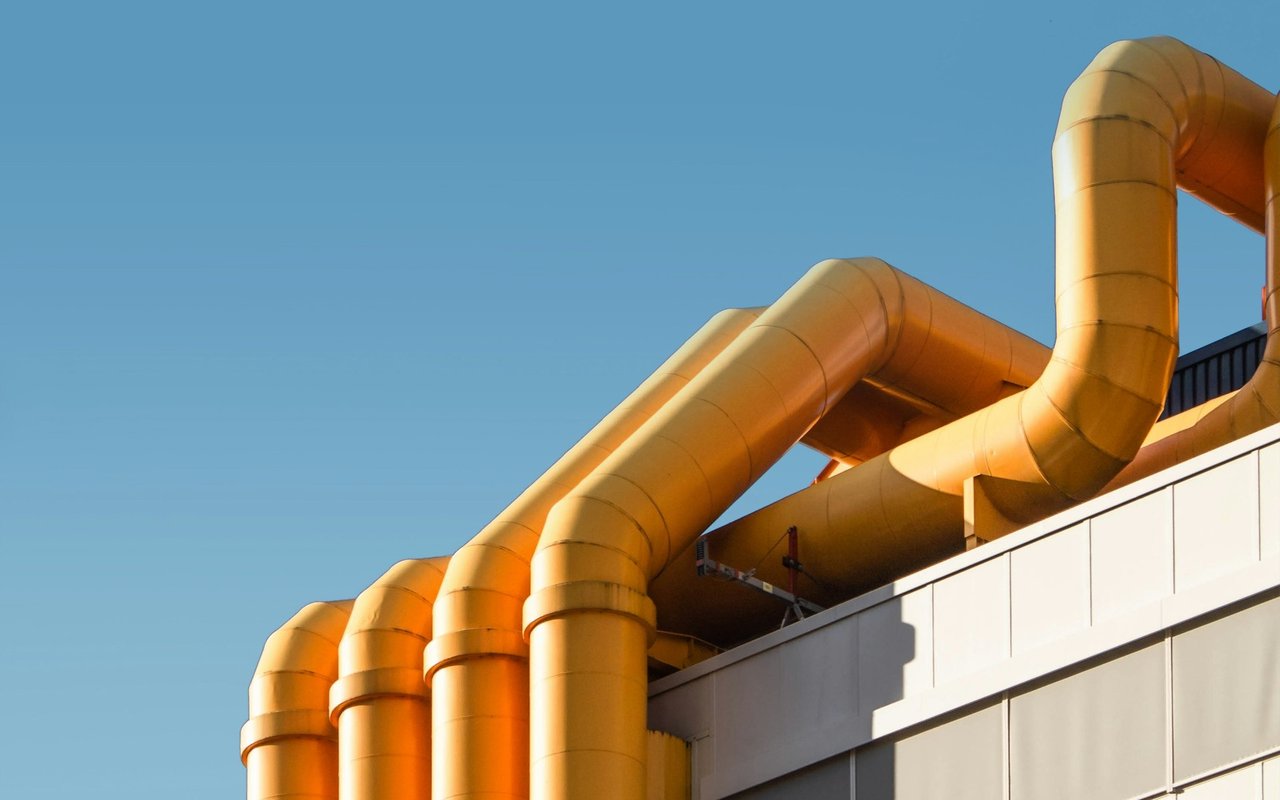 Industrial building with large orange ventilation ducts across its facade.