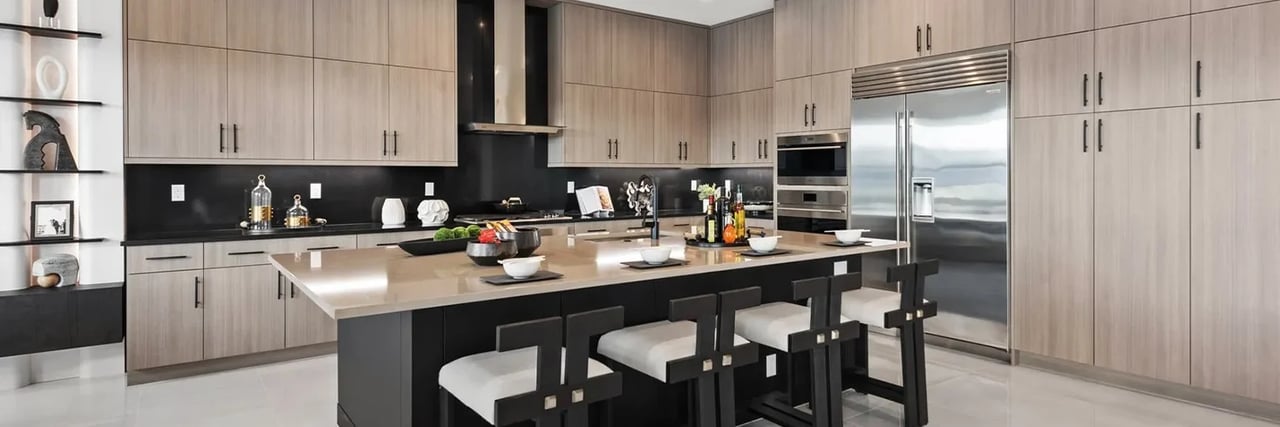Modern kitchen with a large island, light wood cabinets, black backsplash, and stainless steel appliances.
