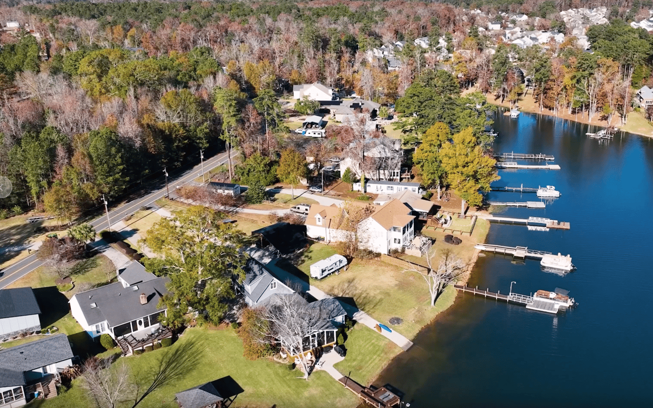 Aerial view of lakefront homes with private docks along a wooded shoreline.