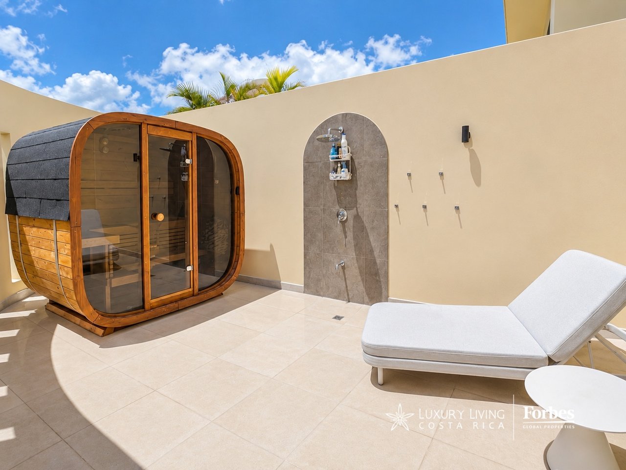 Private terrace with a wooden sauna, outdoor shower and white chaise lounge.