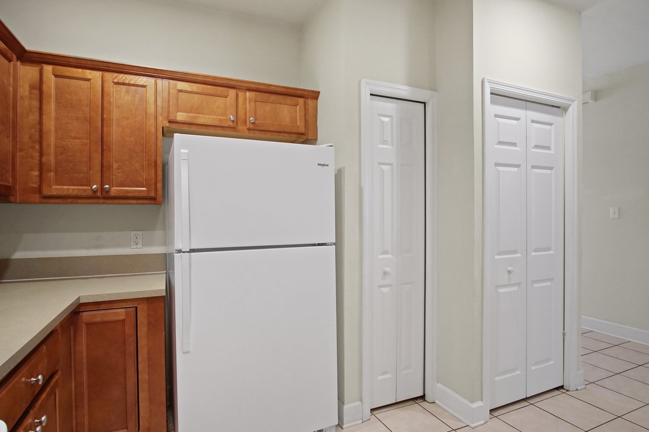 Kitchen at 5441 Hampton Hill Circle, Tallahassee, Florida 32311 featuring wood cabinets, white refrigerator, and pantry doors.
