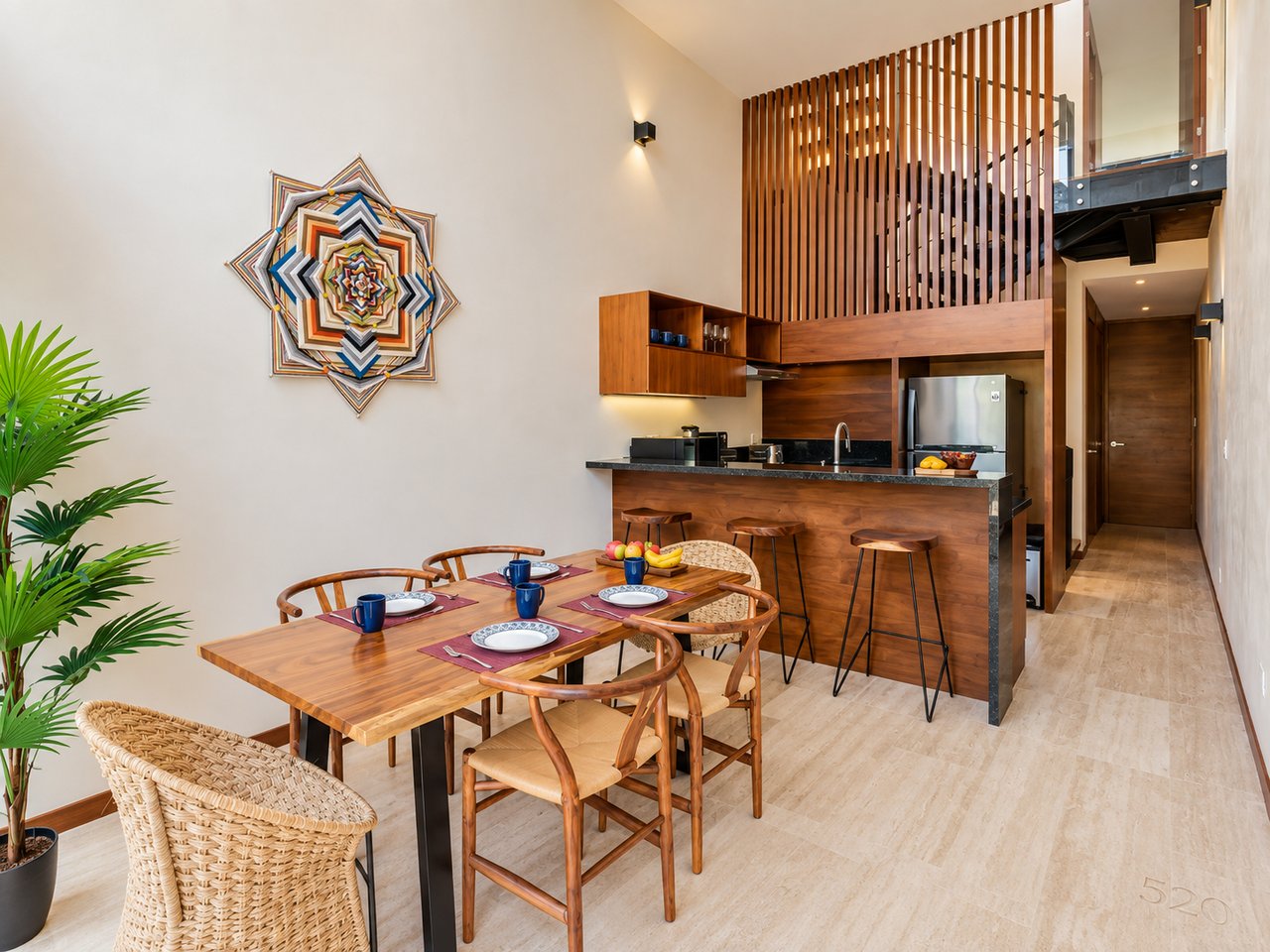 Open-plan dining area and kitchen with a wood dining table and tall slatted divider.