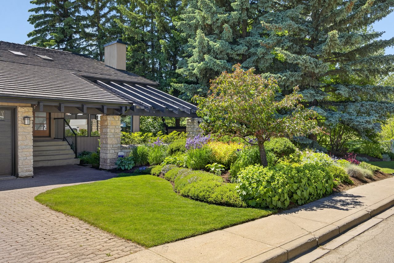 House exterior with stone porch columns and a lush landscaped front garden.