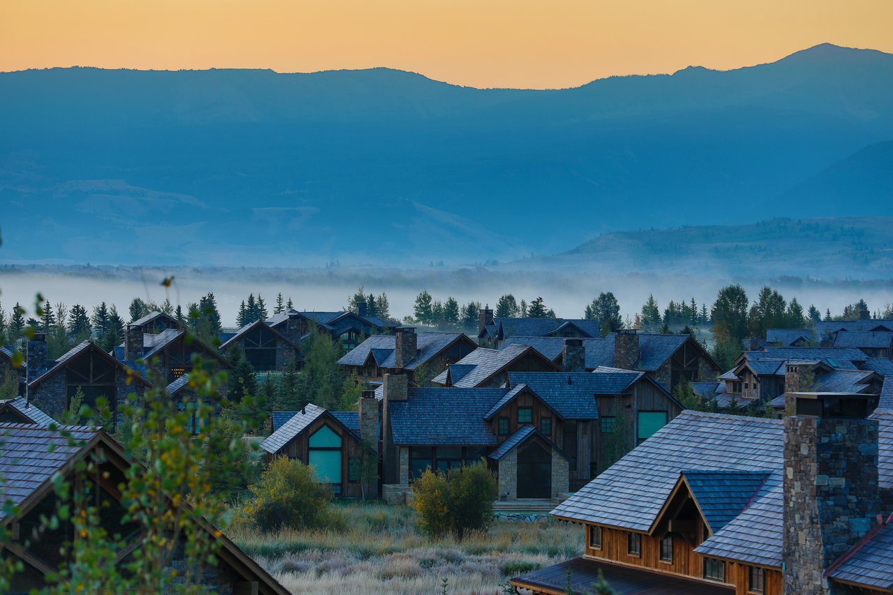 A Jackson Hole real estate agent discussing property options with home buyers in Jackson, WY, with scenic mountains in the background.