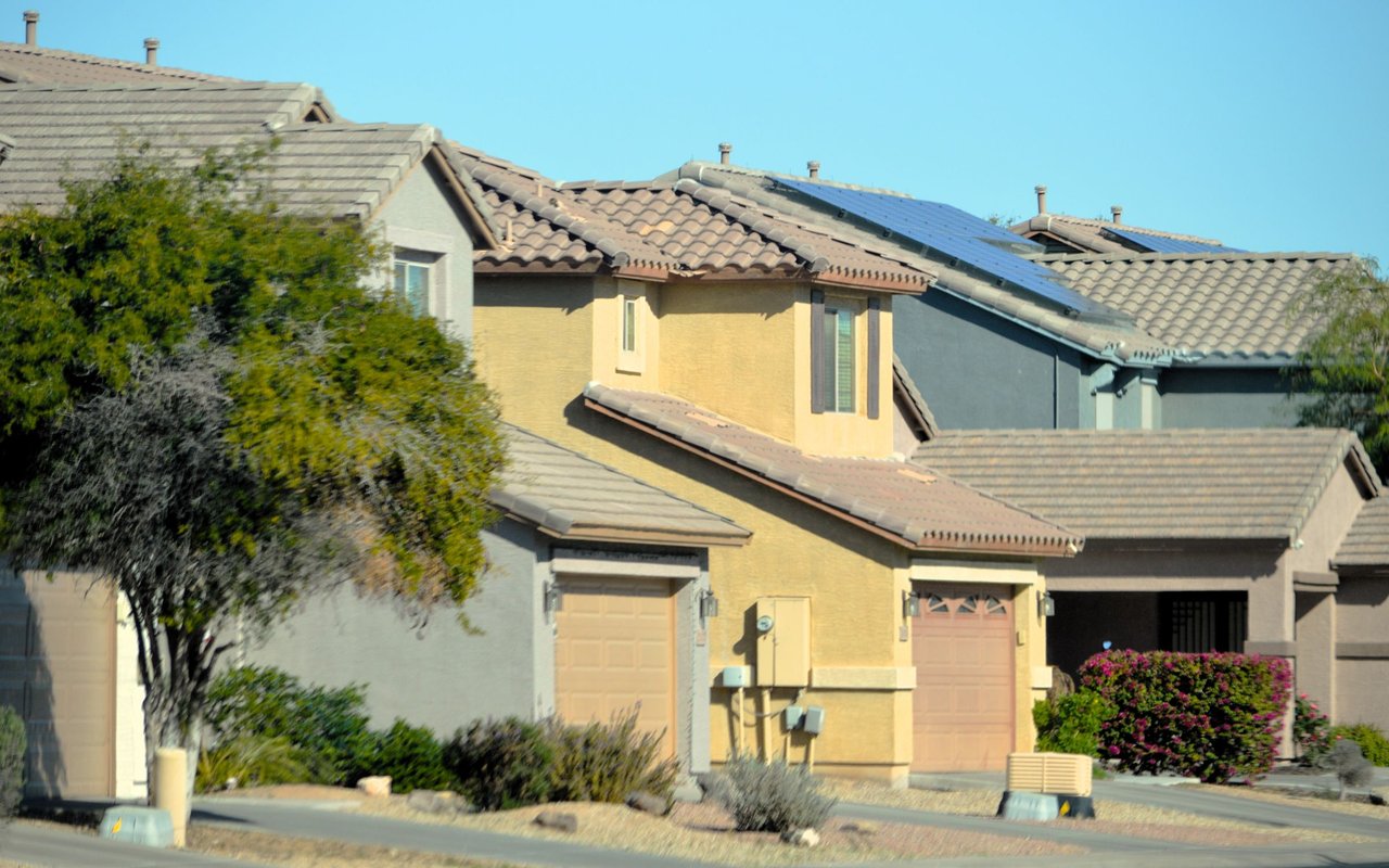 Stucco homes with tiled roofs, rooftop solar panels, and desert landscaping.