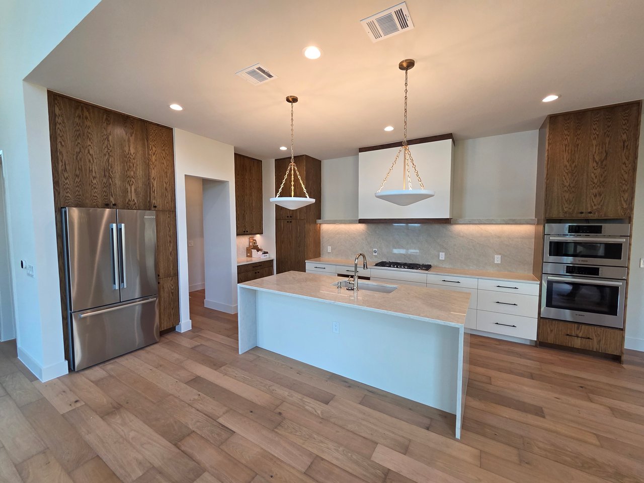 Modern kitchen with a large stone island, dark wood cabinetry, and stainless steel appliances.