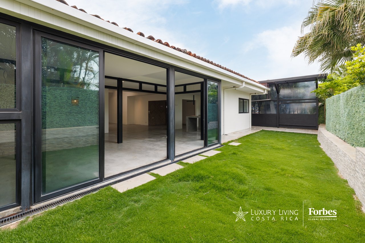 Single-story home opening onto a lawn through black-framed sliding glass doors.