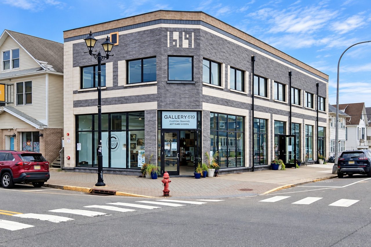 Two-story gray-and-cream commercial building with glass storefronts and Gallery 619 signage.