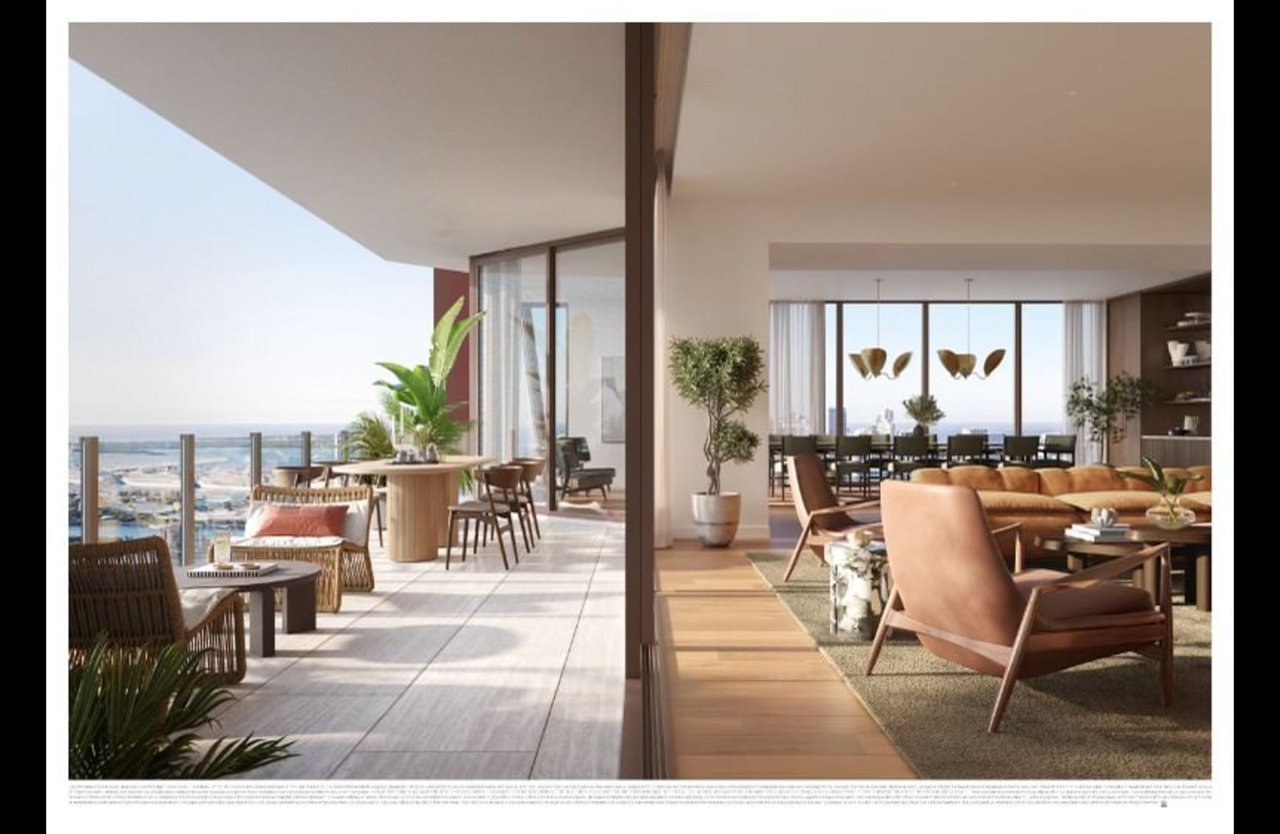 Modern apartment living room opening onto a furnished terrace with glass railings and water views.