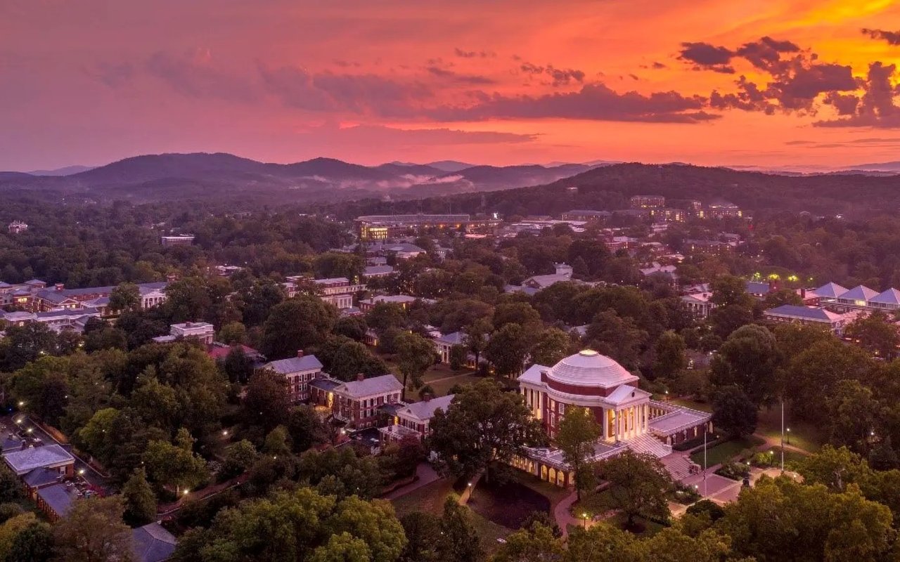 Aerial view of Charlottesville and the University of Virginia Rotunda beneath a vivid sunset.